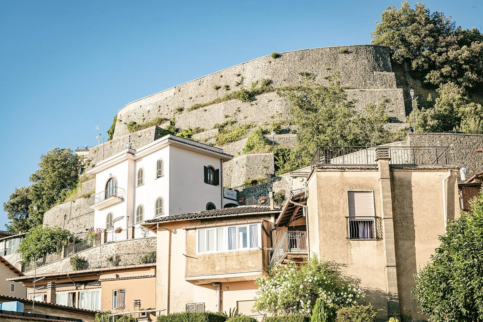 Case del borgo di Rocca di Papa ai piedi delle mura in pietra della rocca, sotto un cielo azzurro